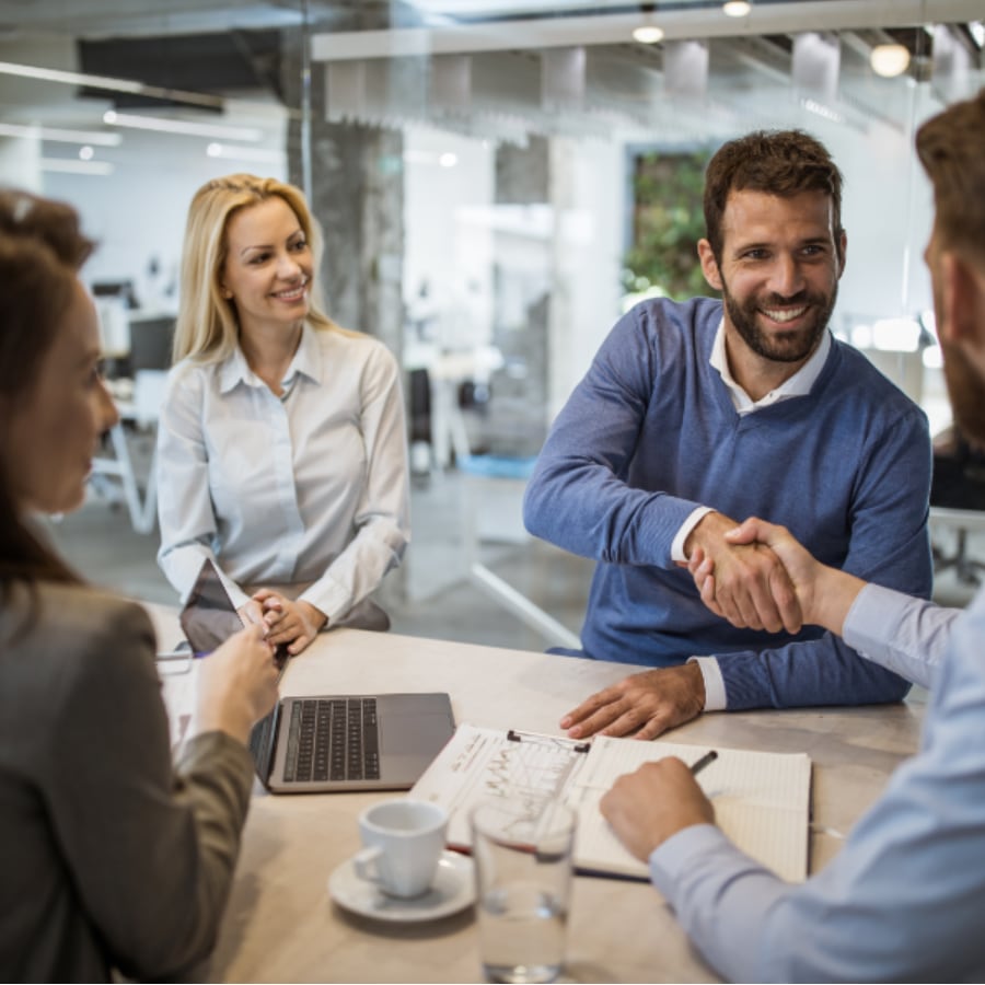 People shaking hands at table during business meeting